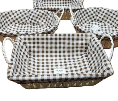 Set of checkered baskets on a wooden table with a laptop and other items in the background.