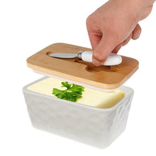Load image into Gallery viewer, Porcelain butter dish with bamboo lid and spreader, holding butter, ideal for kitchen storage.
