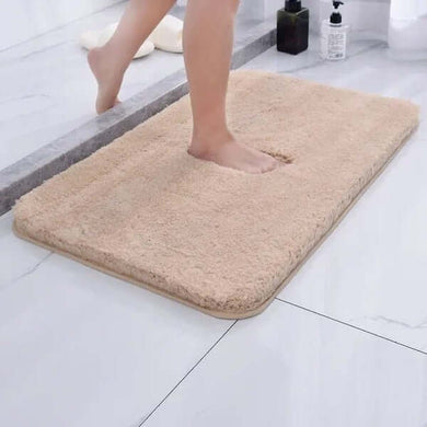 Beige bath mat on a bathroom floor with a person stepping onto it.