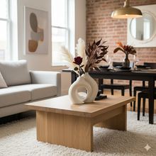تحميل الصورة في عارض المعرض، Living room with a wooden coffee table, decorative vase, and sofa.
