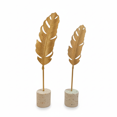 Two gold feather-shaped decorative items on stone bases against a white background
