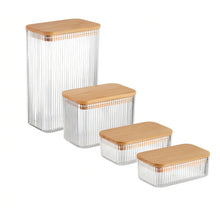Load image into Gallery viewer, Four ribbed clear glass storage containers with light natural wood lids, shown in a nested size progression on a white background.
