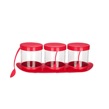 تحميل الصورة في عارض المعرض، Three clear spice jars with red lids and red handles, set on a red tray with a red spoon, isolated on a white background.
