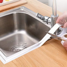 Load image into Gallery viewer, Person using a kitchen faucet with a white handle in a sink.
