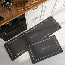 تحميل الصورة في عارض المعرض، Two black kitchen mats with 'KITCHEN' text on a gray floor.
