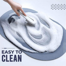 Load image into Gallery viewer, Non-slip bathroom mat with foam and soap being cleaned, showcasing the easy-to-clean feature of the oval-shaped mat.
