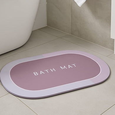 Pink oval anti-slip bath mat with textured surface and drainage holes, positioned on a bathroom floor.