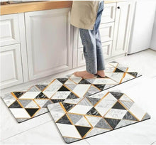 Load image into Gallery viewer, Set of geometric patterned mats on a kitchen floor with a person stepping onto one.
