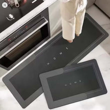 Load image into Gallery viewer, Black heating mats with &#39;HOME&#39; text on a kitchen floor.
