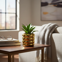 Load image into Gallery viewer, Gold vase with a plant on a wooden table in a living room.
