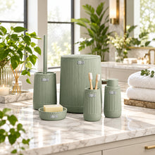 Load image into Gallery viewer, A coordinated bathroom toiletry set in a muted sage green color, including a tall storage jar, a toothbrush holder, a smaller cup, a soap dish with a bar of soap, and a toilet brush, displayed in front of a softly blurred modern bathroom interior.
