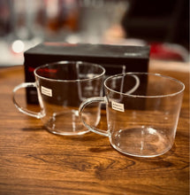 Load image into Gallery viewer, Two clear glass mugs on a wooden surface with a blurred background
