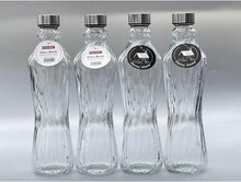 تحميل الصورة في عارض المعرض، Four clear glass bottles with labels on a gray background
