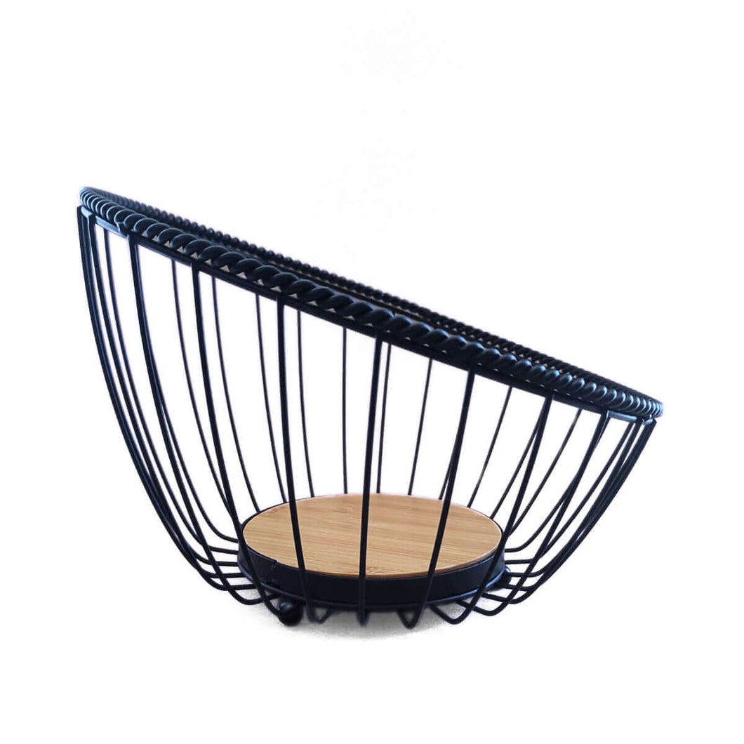 A matte black metal fruit bowl with a round bamboo base designed for storing and displaying fruits.