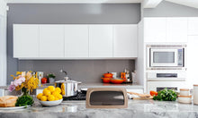 Load image into Gallery viewer, Modern kitchen with white cabinets, marble countertop, and various appliances.

