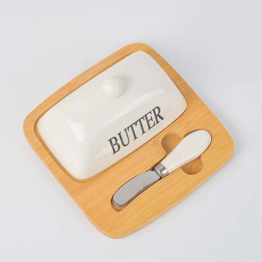 Butter dish with wooden cover and knife on a white background