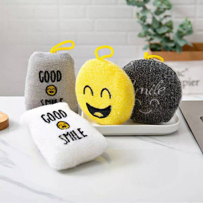 A set of four multi-purpose cleaning sponges in different colors, each with a cheerful face and text elements, displayed on a kitchen counter.