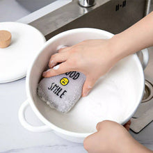 Load image into Gallery viewer, Person washing a gray sponge with text in a white bowl in a kitchen setting.
