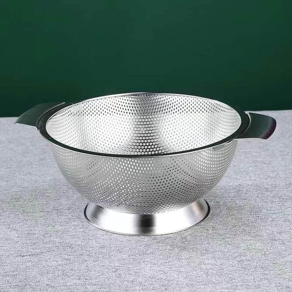 Metallic colander on a gray surface with a green background