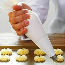 Load image into Gallery viewer, Person using a cream pastry bag to pipe decorative frosting onto baked cupcakes.
