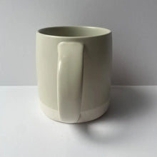 Load image into Gallery viewer, White ceramic mug with a handle on a gray background
