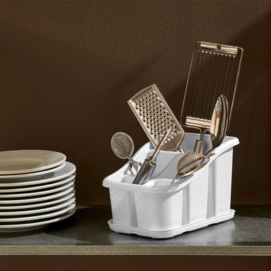 White dish rack with kitchen utensils including a grater and ladle on a brown background