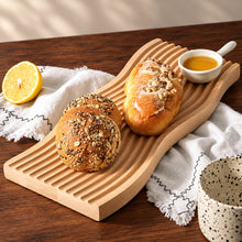 تحميل الصورة في عارض المعرض، Wooden bread board with bread rolls and a lemon on a wooden table.
