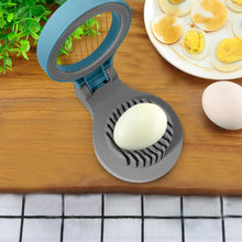 Load image into Gallery viewer, Egg slicer on a wooden cutting board with eggs and a plate of sliced eggs in the background.
