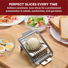 Load image into Gallery viewer, A stainless steel sandwich slicer shown in use on a wooden cutting board, slicing an onion into even rounds. Surrounding plates with sliced bread, salad, and hard-boiled eggs suggest food preparation.
