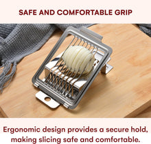 Load image into Gallery viewer, A stainless steel multi-slice onion chopper resting on a wooden cutting board, with sliced white onion inside the grid. Text at the top reads 'SAFE AND COMFORTABLE GRIP' and text at the bottom describes the ergonomic design.
