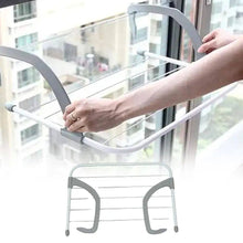 Load image into Gallery viewer, Person using a gray clothes drying rack against a window with a cityscape view.
