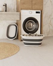 تحميل الصورة في عارض المعرض، Washing machine with a striped laundry basket in a modern bathroom setting

