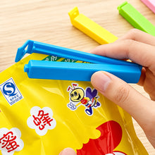 تحميل الصورة في عارض المعرض، Hand using a blue封口器 on a yellow food packaging with cartoon character

