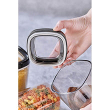 تحميل الصورة في عارض المعرض، Glass food container with a lid being held by a hand, with food visible inside.
