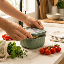 Load image into Gallery viewer, Green food storage container with lid held by hands on a neutral background
