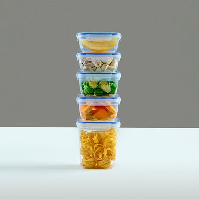 Stack of four food storage containers with different types of food on a gray background