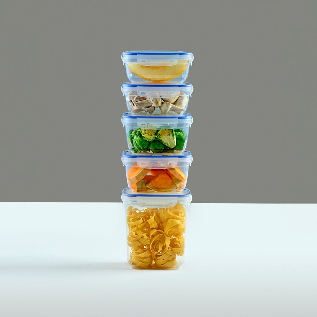 Stack of four food storage containers with different types of food on a gray background