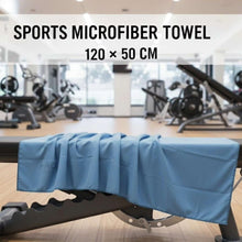 تحميل الصورة في عارض المعرض، Blue sports microfiber towel draped over a gym bench with gym equipment in the background
