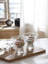 Load image into Gallery viewer, Two glass dessert stands with small cakes on a wooden board in a bright room.

