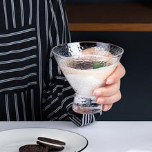 Load image into Gallery viewer, Hand holding a glass with a layered dessert, wearing a black and white striped shirt.
