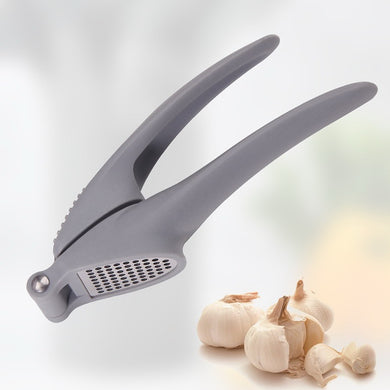 Gray garlic press with garlic cloves on a light background
