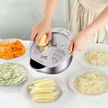 Load image into Gallery viewer, Person using a vegetable peeler to create various sliced vegetables on a white surface.
