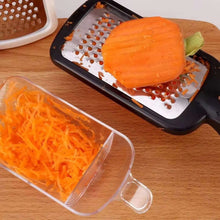 تحميل الصورة في عارض المعرض، Carrot being grated on a manual grater with shredded carrot in a container on a wooden surface.
