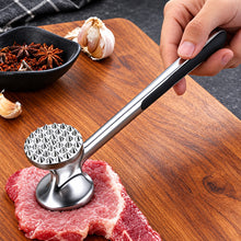 Load image into Gallery viewer, Metal meat tenderizer on a piece of meat with garlic and spices in the background
