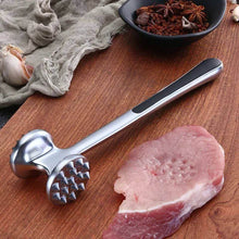 Load image into Gallery viewer, Metal meat tenderizer on a wooden surface with a piece of raw meat and a bowl of spices.
