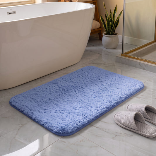 Misty blue shaggy microfiber bath mat on a bathroom floor beside a bathtub