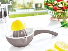 Load image into Gallery viewer, Handheld lemon squeezer on a kitchen counter with lemons and a salad in the background.
