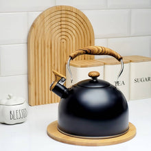 Load image into Gallery viewer, Black kettle with wooden handle on a white surface with kitchen items in the background
