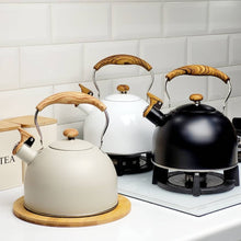 Load image into Gallery viewer, Set of three kettles with wooden handles on a kitchen counter.

