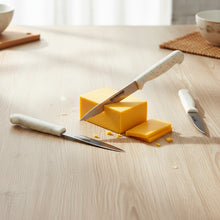 Load image into Gallery viewer, Two pieces of cheese with knives on a wooden surface
